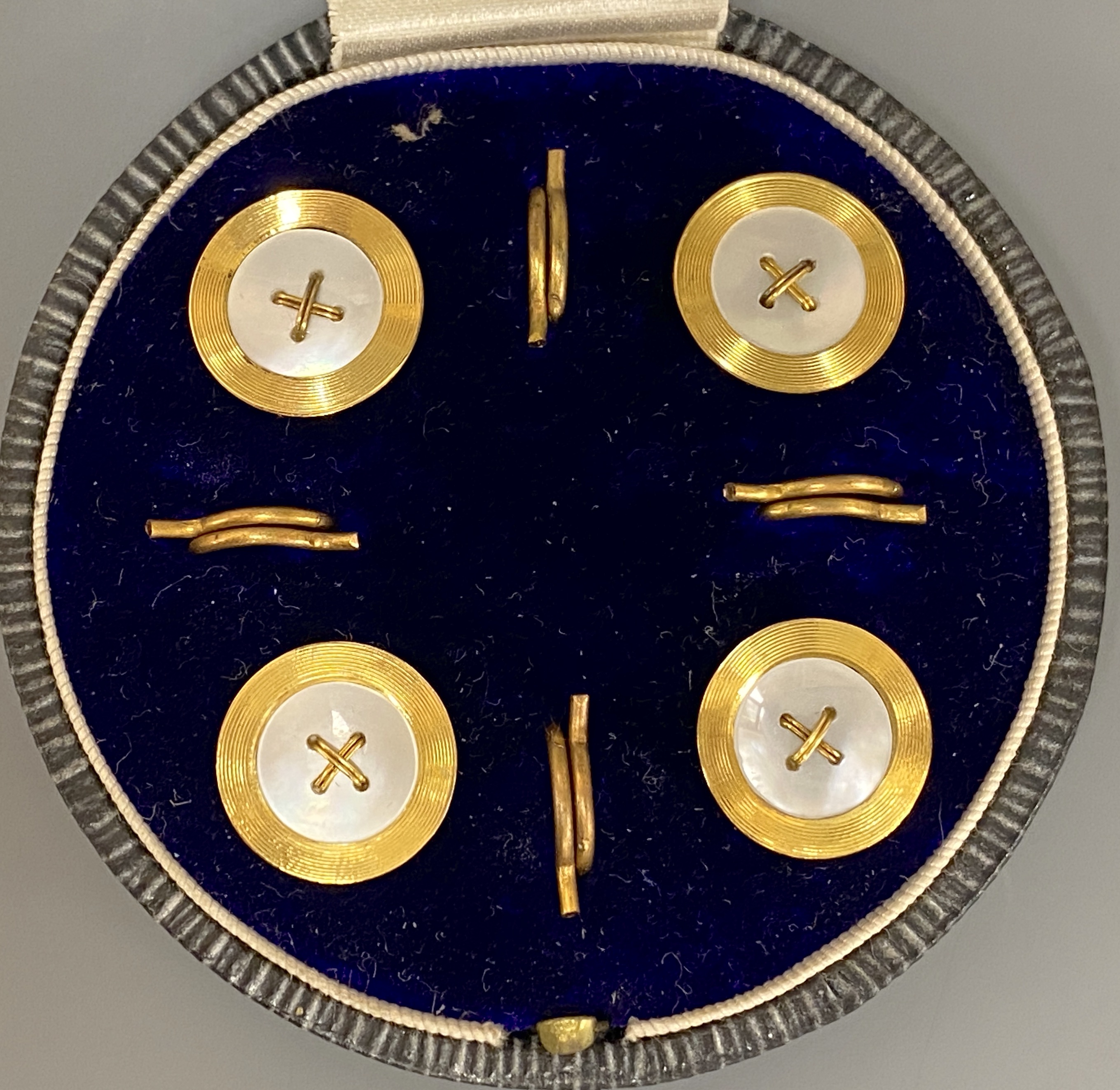 A cased set of four early 20th century 9ct and mother of pearl set buttons